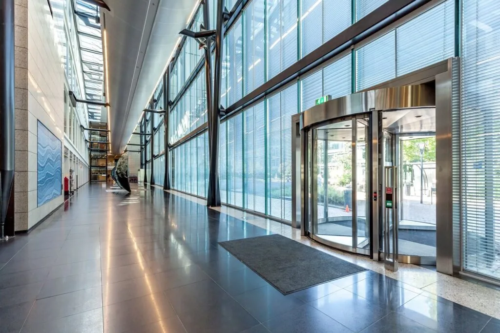 Moderne, lichte entreehal van Kessler Park met glazen wanden, kunstobject en draaideur.